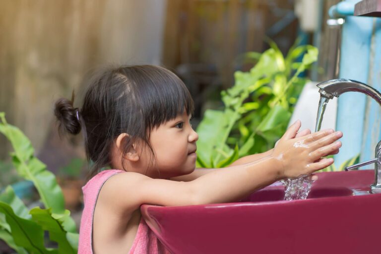 A child washing their hands after playing outside.