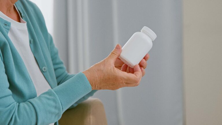 Mature woman patient takes blank white bottle of medicine from doctor.