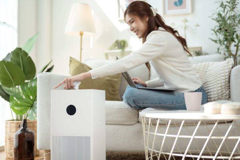 Woman using Air Purifier while working on laptop in cozy living room with indoor plants