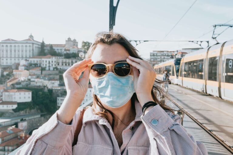 A person wearing sunglasses and a mask outside on a windy day.