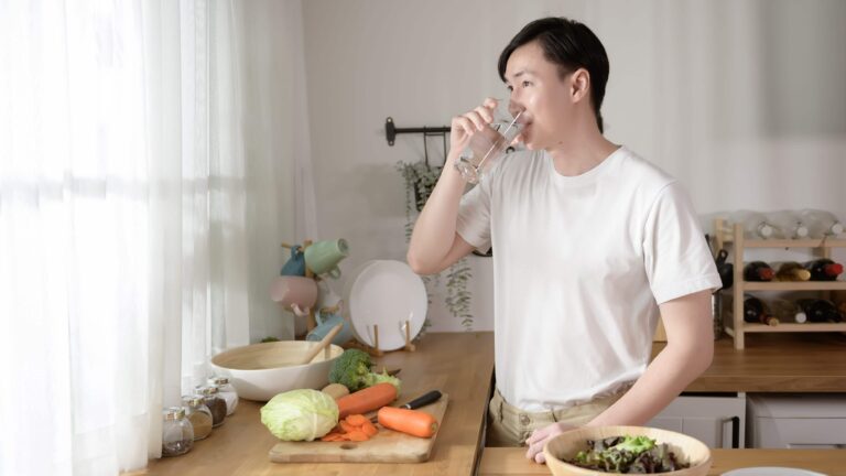 young-man-drinking-fresh-water-in-kitchen-at-home