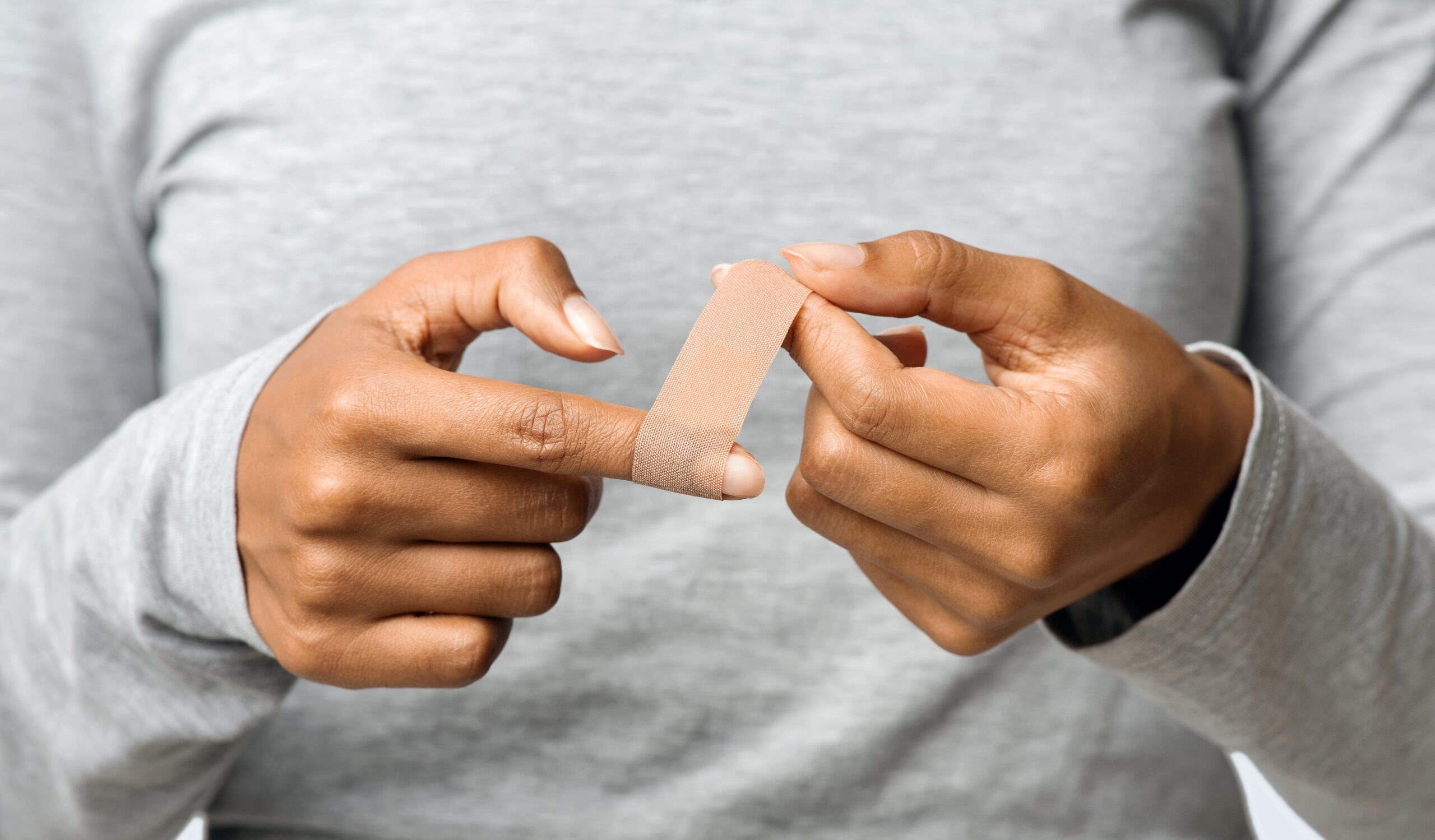 afro-woman-using-adhesive-tape-on-injured-finger