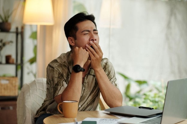 man yawning in front of computer