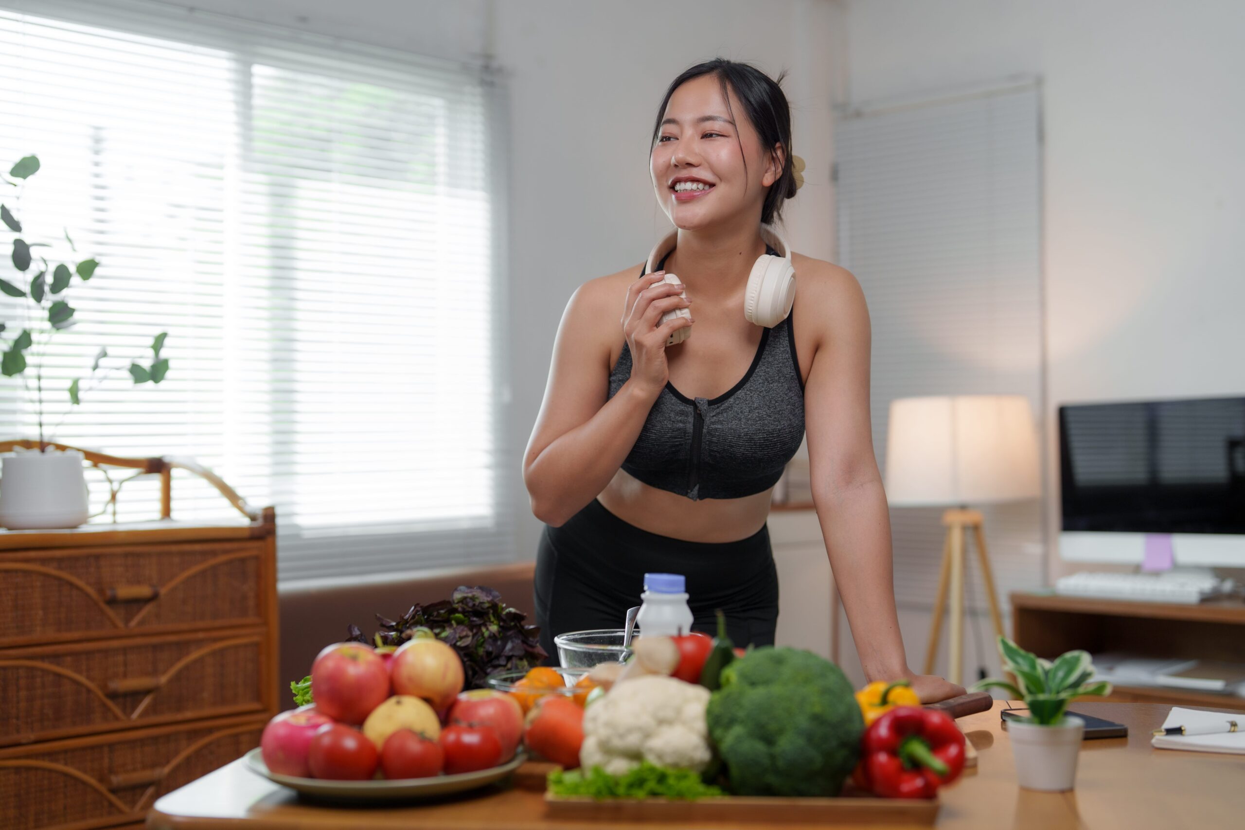 Young asian sportswoman eating healthy food and smiling after training at home