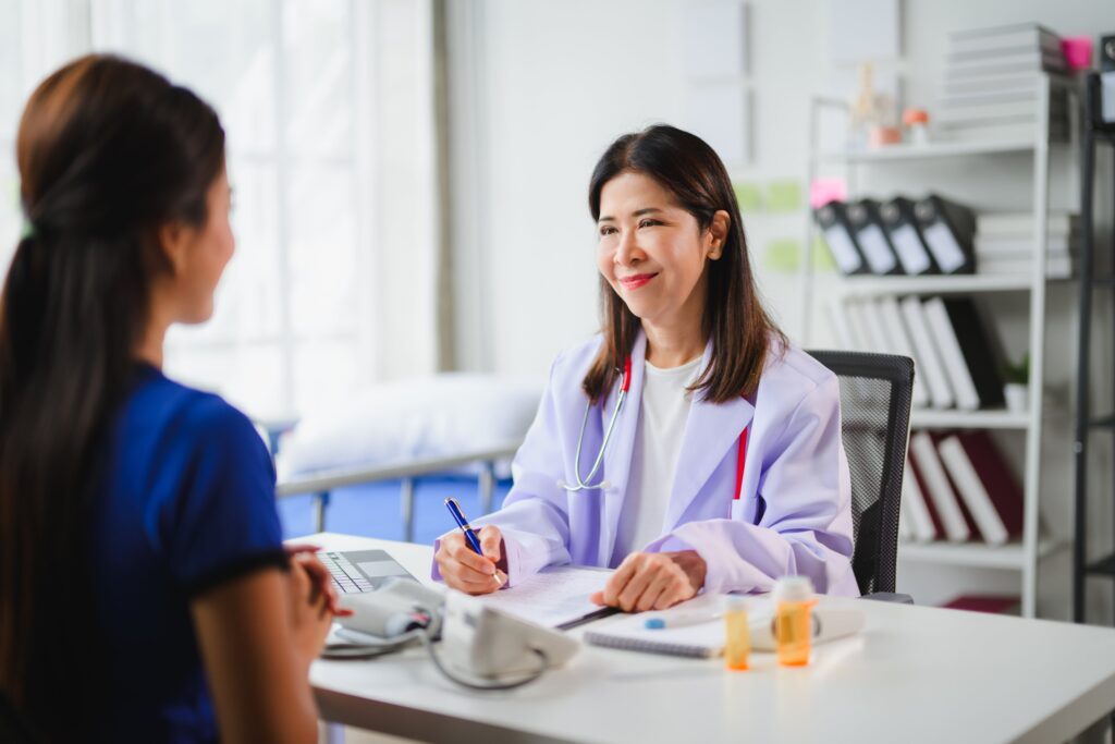 Doctor taking notes while listening to the patient explaining her symptoms