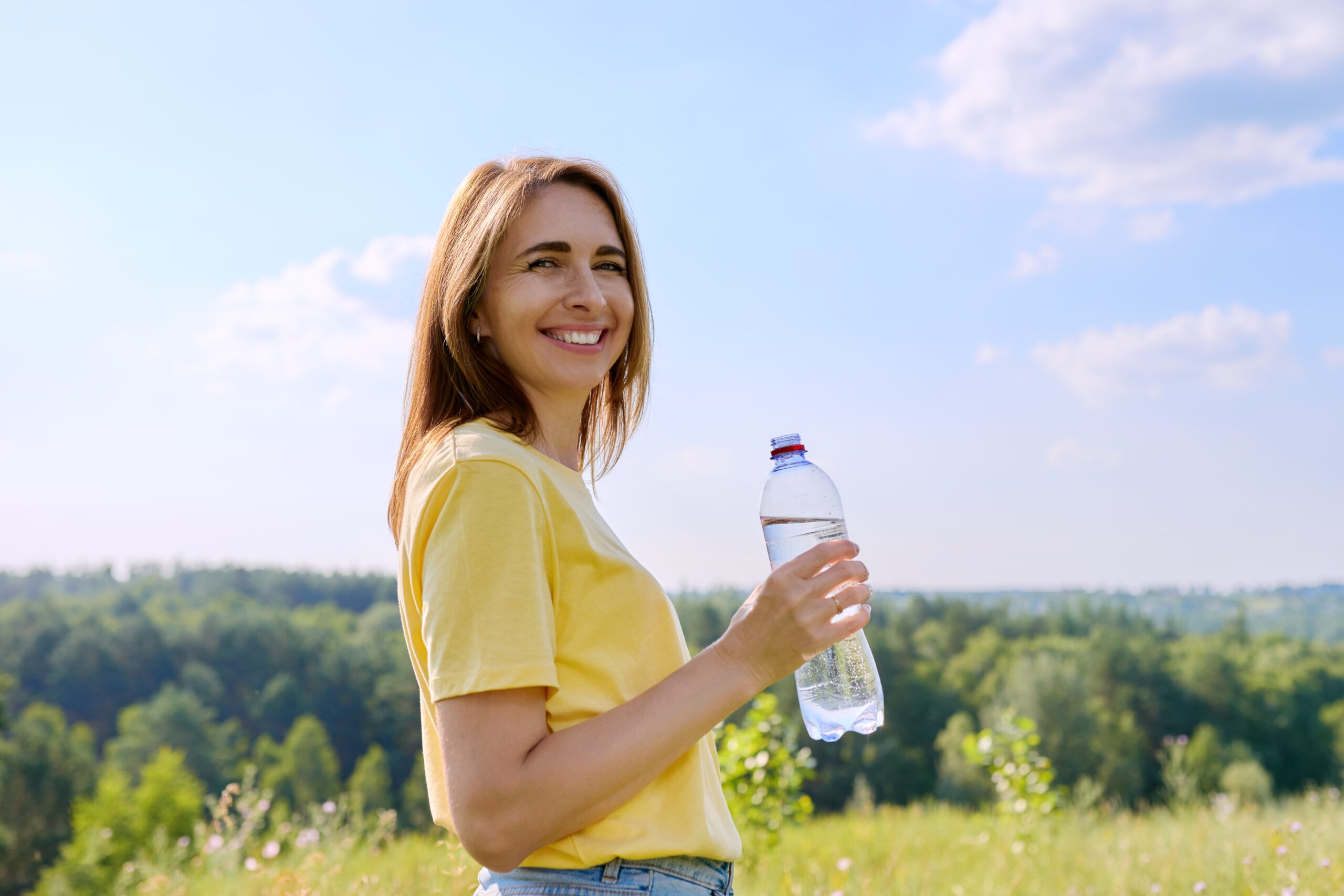 Hot sunny summer, a woman with a bottle of water looking at the camera.