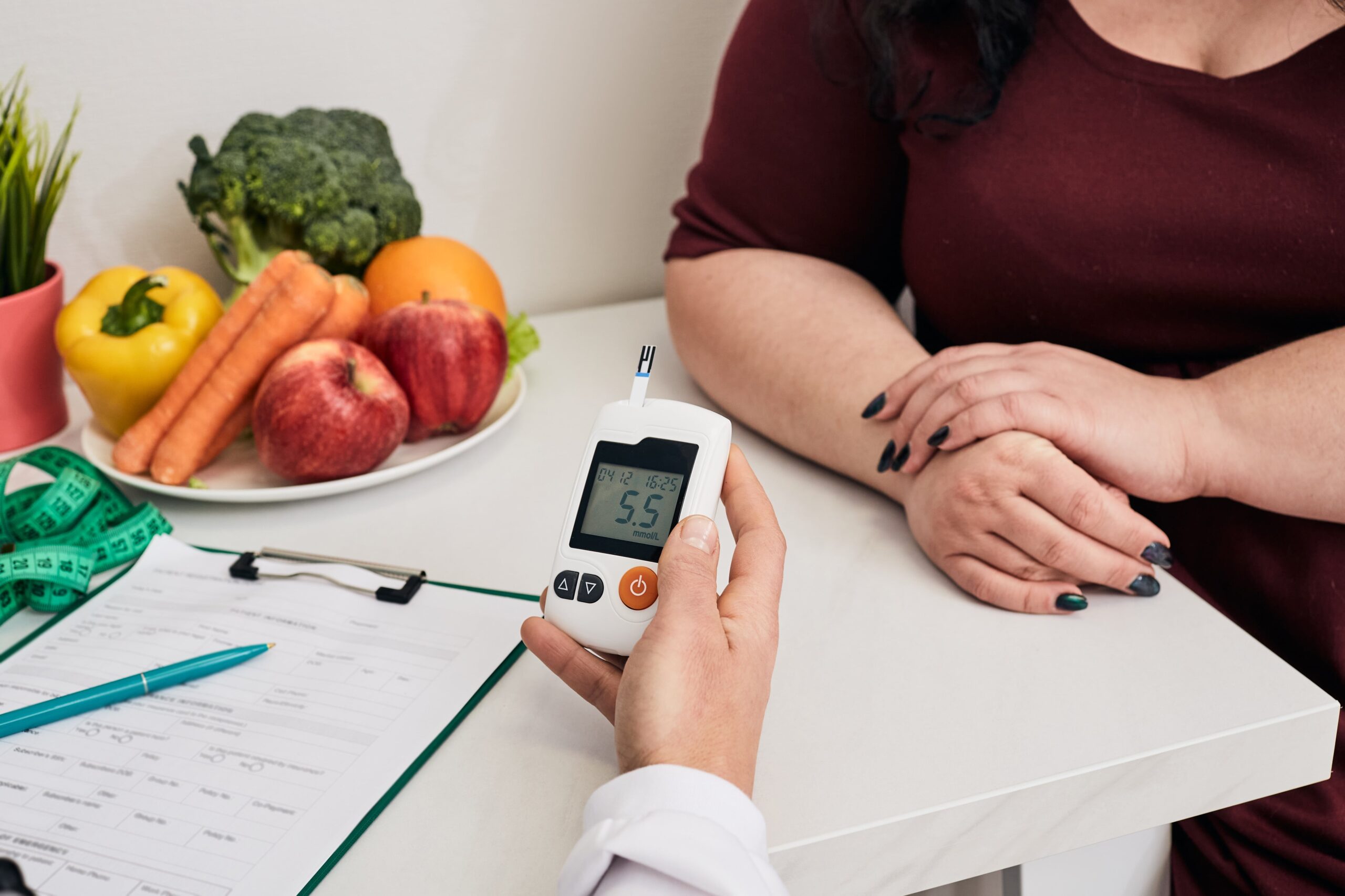 Measuring blood sugar. A nutritionist using a glucometer tests an overweight woman's blood sugar.