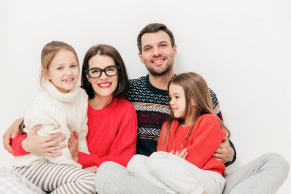 A family sitting together in a warm, cozy living room, wearing comfortable sweaters, with gentle winter sunlight coming through the window.