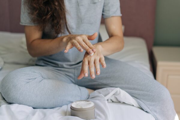 An unrecognizable woman uses hand cream.