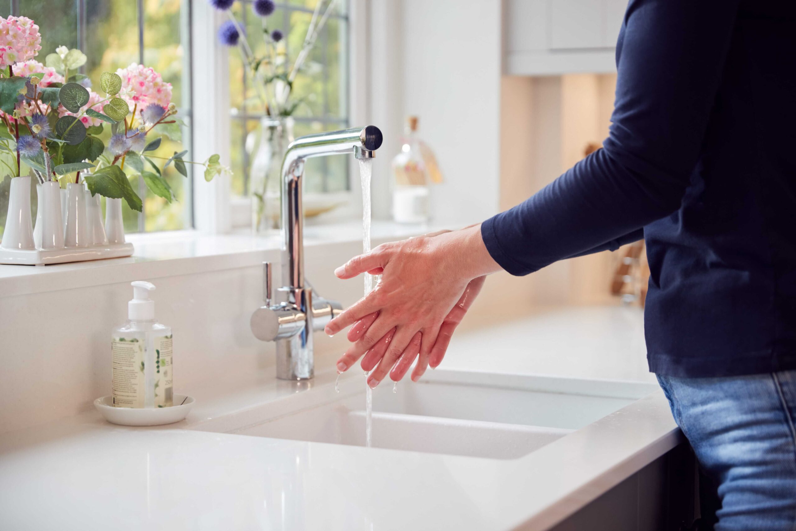 Close-up of a woman washing her hands with soap at home.